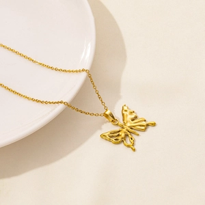 Detail shot of a golden butterfly pendant necklace on a textured beige fabric background