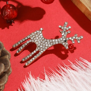 Détail de la broche renne de Noël dorée avec strass sur un fond rouge festif chic