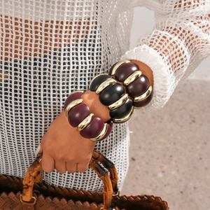 Macro shot of chunky geometric resin bangles in deep purple and black with gold rings
