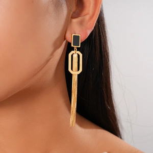 Détail de boucles d'oreilles pompon plaquées or 18 carats avec gemme noire sur modèle