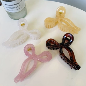Detail view of colorful bow-shaped hair claws in white, beige, pink, and tortoiseshell