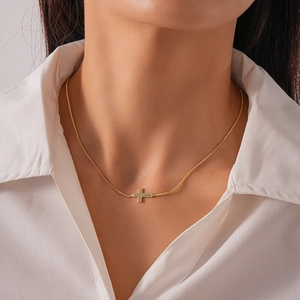Close-up of 18k gold plated cross pendant necklace worn by a model in a white shirt