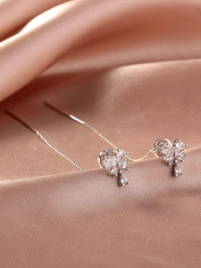Detail of silver tassel earrings with flower rhinestones on champagne silk fabric