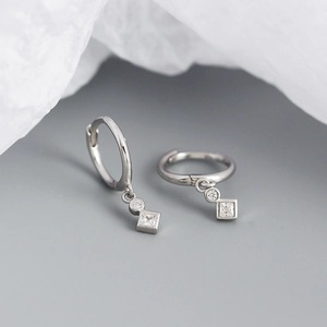 Macro shot of silver square cubic zirconia drop earrings on a soft grey surface