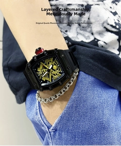Close-up of tonneau sport watch with red crown and silver chain on model wrist