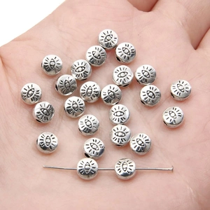 Close-up of silver alloy heart eye charms for DIY jewelry making held in a hand