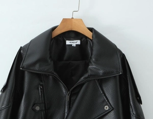 Details von schwarzer Lederjacke mit Reißverschlusstasche vor weißem Hintergrund