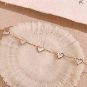 Detail of 18K gold plated bracelet featuring five white mother of pearl heart pendants