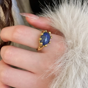 Close-up of gold-plated oval lapis lazuli stone ring with handcrafted hammered texture