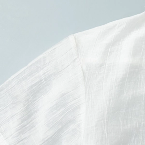 Dettaglio della texture del lino bianco e delle cuciture sulla spalla della camicia