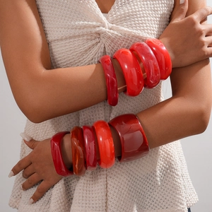 Close-up of a model wearing stacked vintage red resin bangles with a geometric round design
