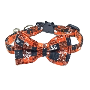 Detailed view of festive orange and black plaid pet collar with snowflake print and silver bell