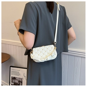 Close-up of white leather crossbody bag featuring gold flower studs and pleated cloud base