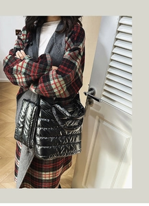 Detail view of large black quilted puffer tote bag with glossy finish on a stylish model