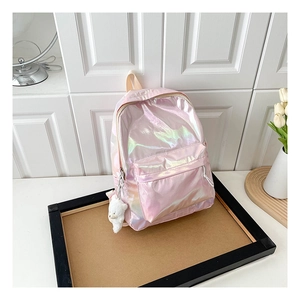 Detail eines rosa holografischen Rucksacks mit süßem weißem Plüschbär-Anhänger