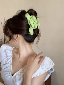 Close-up of a grass green pleated fabric hair scrunchie on a brown updo hairstyle