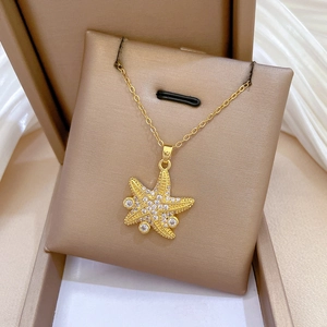 Starfish pendant necklace in gold with shimmering crystals on a brown display pad
