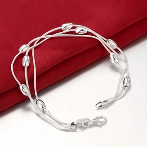 Detail of silver multi-layer bracelet with oval beads on elegant red fabric