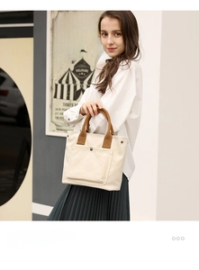 Detailed view of the casual canvas tote bag featuring sturdy brown handles and a pocket.