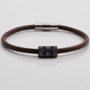 Detail of brown braided leather bracelet featuring a purple stone and magnetic clasp