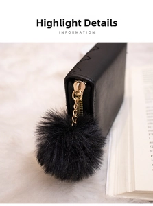 Detail of black quilted leather wallet with gold zipper and faux fur pompom charm