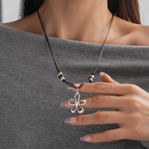 Détail d'un pendentif fleur argenté avec perles céramiques sur cordon de cire noir