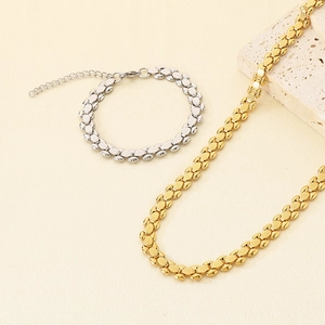Detail view of gold and silver watch-strap style metal jewelry set on textured stone