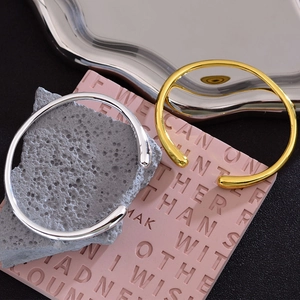 Minimalist silver and gold Rupert teardrop open bangles displayed on stylish props