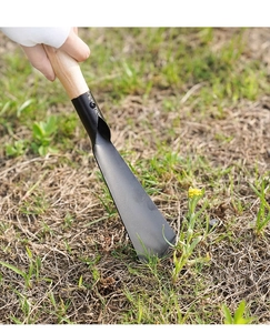 Close-up of a manganese steel garden trowel with a natural wooden handle on green grass