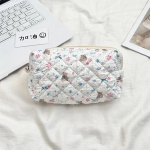 Detailed view of quilted cotton pouch featuring cartoon bear patterns on a desk