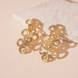 Detailed macro of gold metallic triple-flower earrings with radial textured petal finish