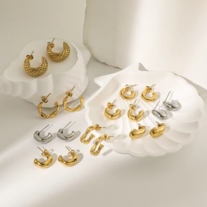18K gold and silver geometric C-shaped earrings on textured white display tray