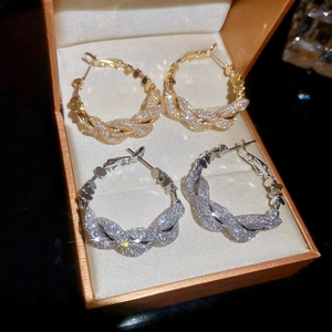 Close-up of twisted gold and silver hoop earrings with sparkling texture in a box