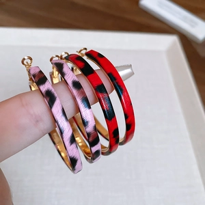 Close-up of leopard print hoop earrings in rose pink and bright red with gold interior