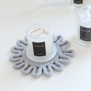 Close-up of grey woven cotton coaster under a soy wax scented candle in glass jar