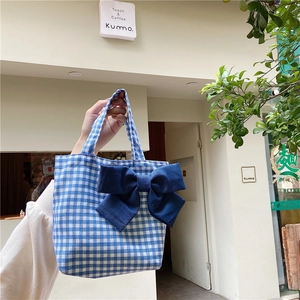 Close-up of blue plaid lunch bag featuring a large decorative dark blue bow detail