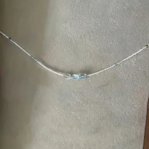 Gros plan d'un collier de perles artisanal avec pierres bleues sur texture pierre grise