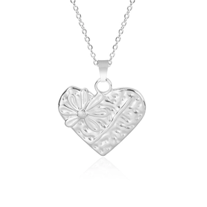 Vue macro du pendentif cœur argenté avec texture martelée et détails de fleurs en 3D