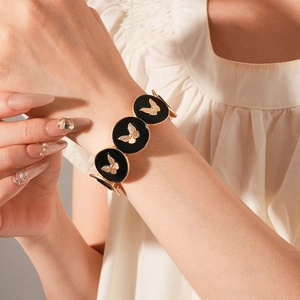 Detail of vintage gold bracelet with black enamel links and butterfly relief pattern