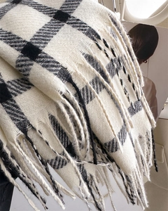 Close-up of classic black and white plaid scarf featuring soft cashmere-like texture and fringe