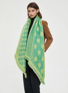 Detail of green polka dot thick winter scarf with soft tassels worn by a model