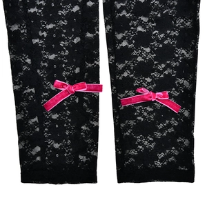 Detailed view of black lace jumpsuit featuring delicate floral patterns and pink velvet bows