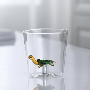 Cute glass cup with green and yellow turtle figurine inside minimalist glassware