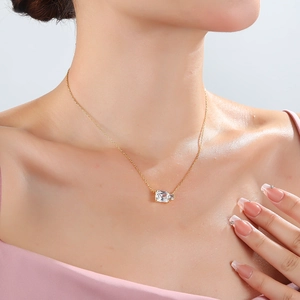 Close-up of minimalist gold necklace with rectangular and round clear gemstone on model