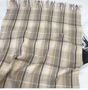 Macro detail of beige British plaid scarf with soft fringe and warm cashmere feel