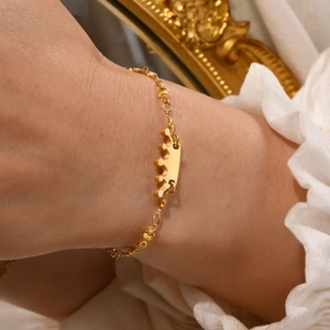 Detail of gold crown bracelet with heart links on wrist against vintage background
