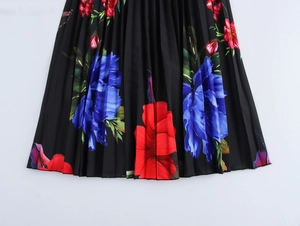 Détail du tissu plissé noir avec imprimé floral rouge et bleu sur robe longue