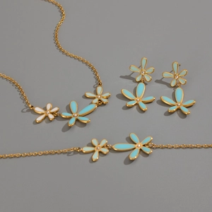 Detail view of 18K gold plated jewelry set with blue and white enamel flowers