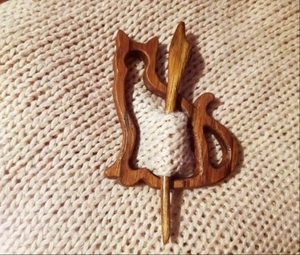 Detailed close-up of a wooden cat brooch and pin fastener on a beige knitted sweater