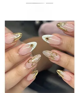 Close-up of French 3D almond press-on nails with golden edges and rhinestone star charms